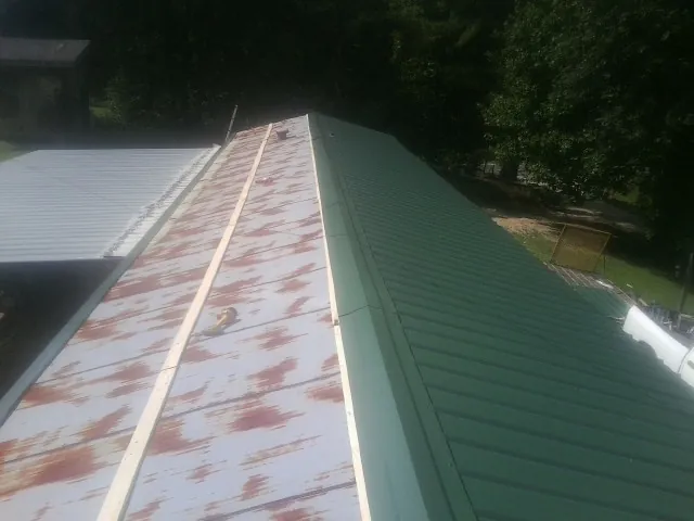 Old rusted panels beside newly installed green metal roofing — Wind Damage Roof Repair by Roofing Brothers in Fillmore