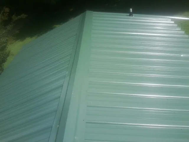 New green metal panels meeting at the ridge of a roof — Flat Roof Repair work by our crew in Fillmore