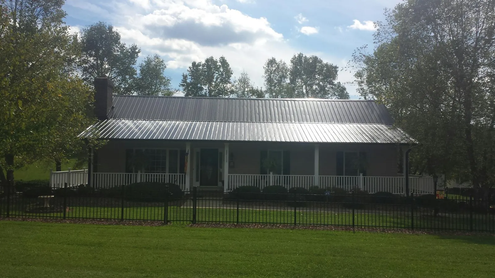 Gray metal roof on a brick ranch with a full width front porch — Gutter Guard Installation work by our crew in Fillmore