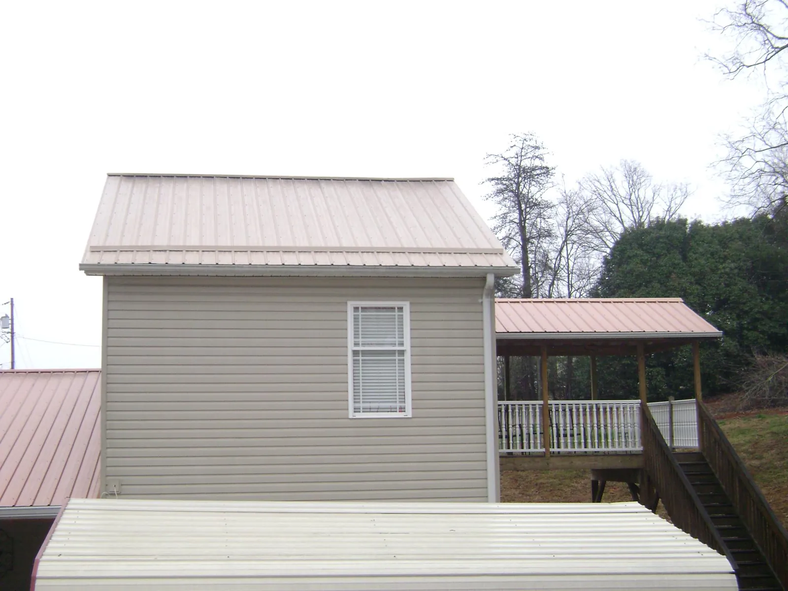 Tan metal roofs on a two story addition and attached porch, from a Roof Replacement job in Fillmore