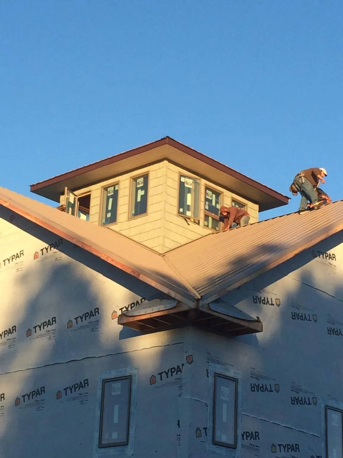 Roofers working around a rooftop cupola on a new metal roof at sunset — Roof Waterproofing in Fillmore by Roofing Brothers